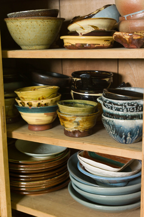 Stacks of homemade pots in a kitchen cupboard